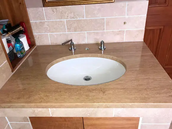 Travertine vanity surface with an inset basin