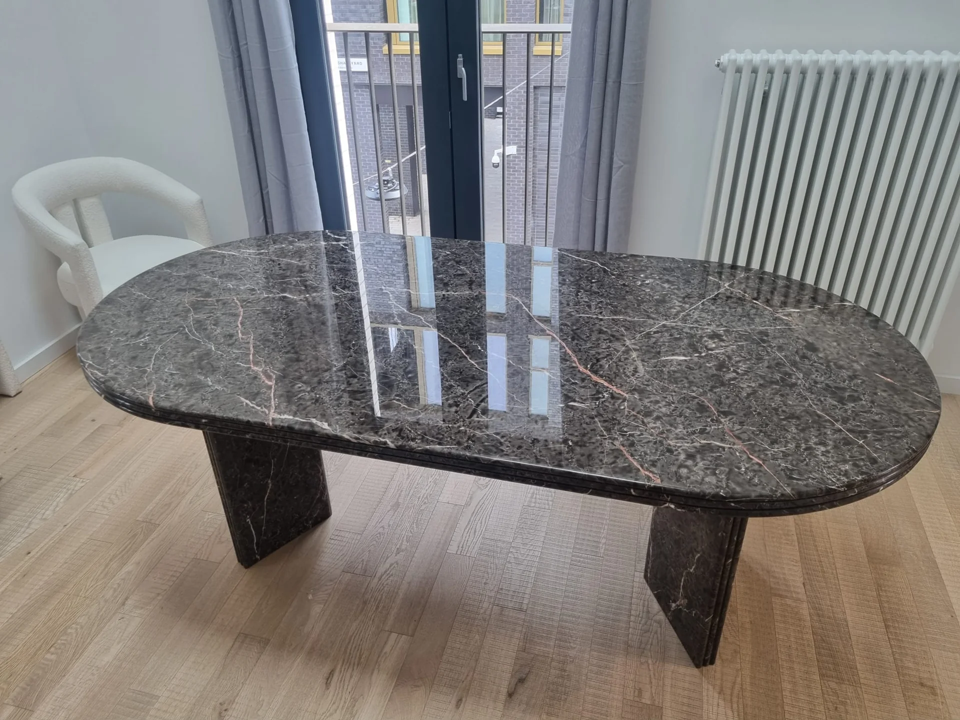 Dark patterned oval stone table reflecting the light from nearby doors