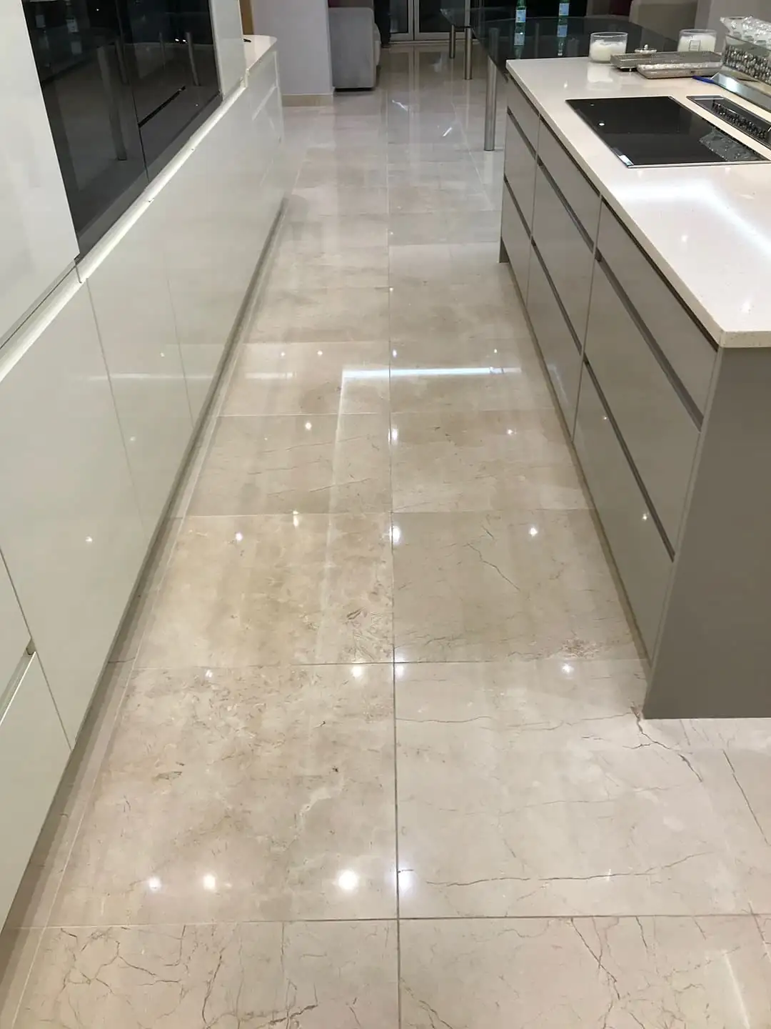 Veined marble floor beside kitchen cabinetry