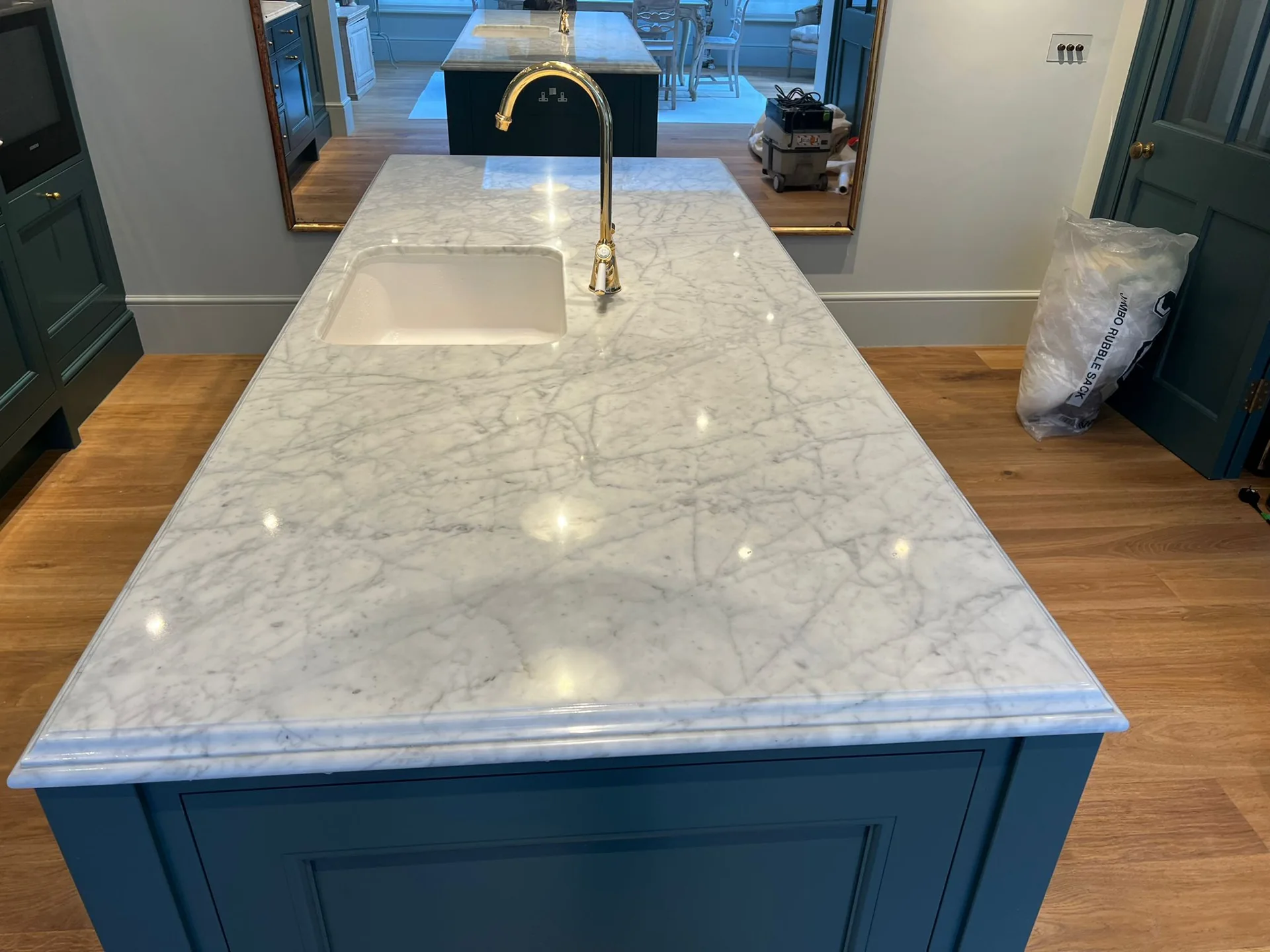 Pale veined stone island worktop with a sink and blue cabinetry